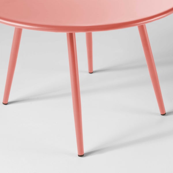 Runder Gartentisch aus Metall in Rosa mit vier schlanken Tischbeinen.