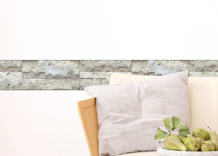 Verblendsteine in Natursteinoptik als horizontaler Wandstreifen in einem hellen Wohnzimmer mit Sofa.