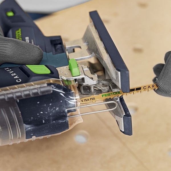 Detailaufnahme einer Stichsäge mit eingesetztem Sägeblatt beim Sägen von Holz.