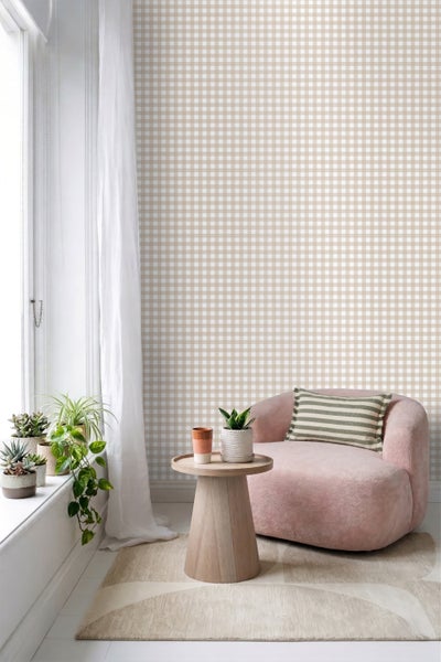 Heller Raum mit beige-weiß karierter Tapete, Sessel, hölzernem Beistelltisch und Zimmerpflanzen auf der Fensterbank.