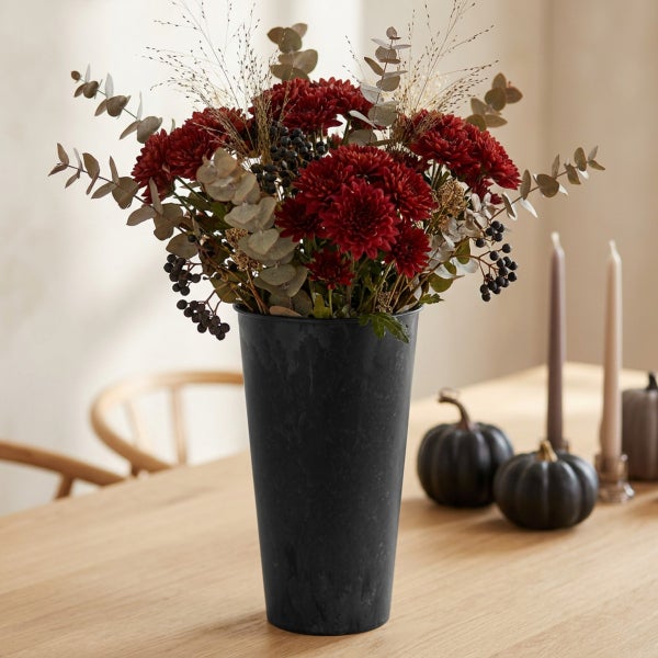 Herbstlicher Blumenstrauß mit Chrysanthemen und Eukalyptus in einer schwarzen Vase auf einem Holztisch mit dekorativen Kürbissen.