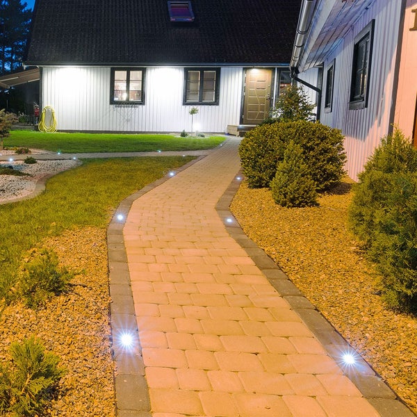 Beleuchteter Gartenweg mit Pflastersteinen zu einem Haus