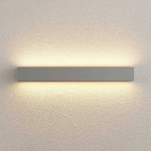 Moderne rechteckige LED-Wandleuchte mit Lichtaustritt nach oben und unten an einer strukturierten Wand.