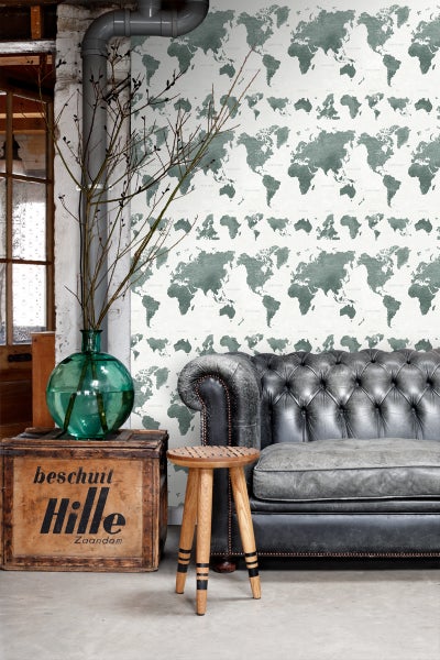 Wohnzimmer mit Weltkarten Tapete, Ledersofa und Holzhocker