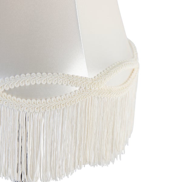 Lampenschirm aus weißem Stoff mit dekorativer Borte und Fransen.