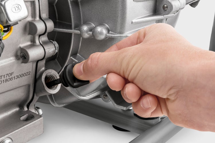 Hand beim Einsetzen eines Ölmessstabs in den Motor eines Stromerzeugers zur Kontrolle des Ölstands.