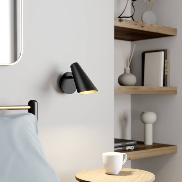 Schlafzimmer mit schwarzer Wandleuchte, Nachttisch und Regal