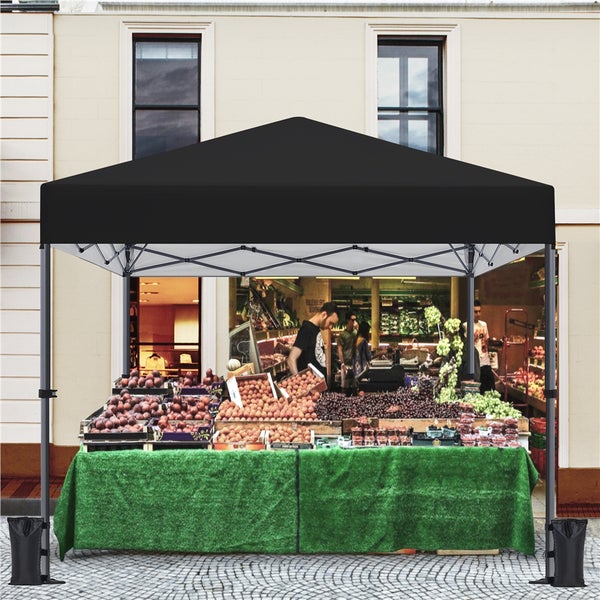 Schwarzes Faltzelt über einem Verkaufsstand mit Obst und Gemüse vor einem Gebäude