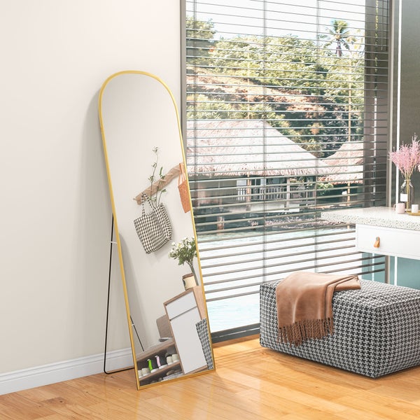 Ganzkörperspiegel mit goldenem Rundbogen-Rahmen, freistehend in einem hellen Zimmer auf Holzboden.
