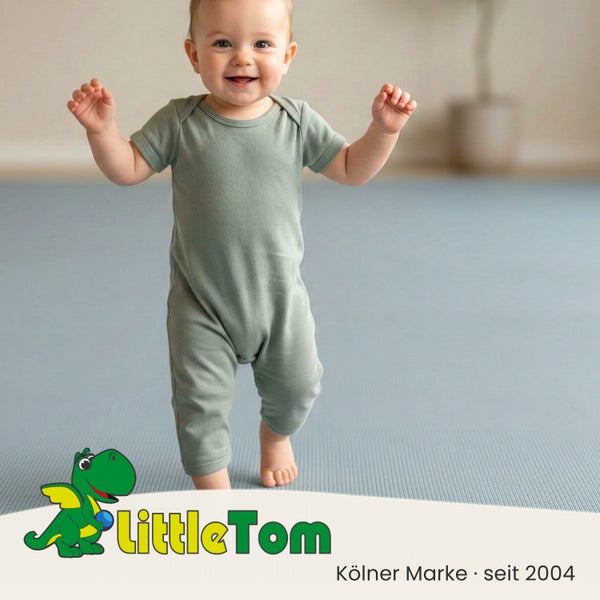 Kleinkind auf einer blauen, strukturierten Spielmatte oder Bodenschutzmatte. LittleTom Logo.