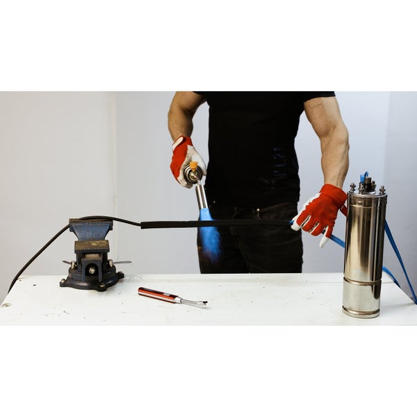 Eine Person lötet Kupferrohre mit einem Gasbrenner auf einer Werkbank.