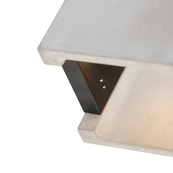 Nahaufnahme einer Wandleuchte aus Beton mit schwarzem Metallelement und warmem Licht.