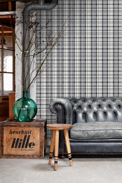 Dekoratives Wohnzimmer mit karierter Tapete, Ledersofa und Holzhocker