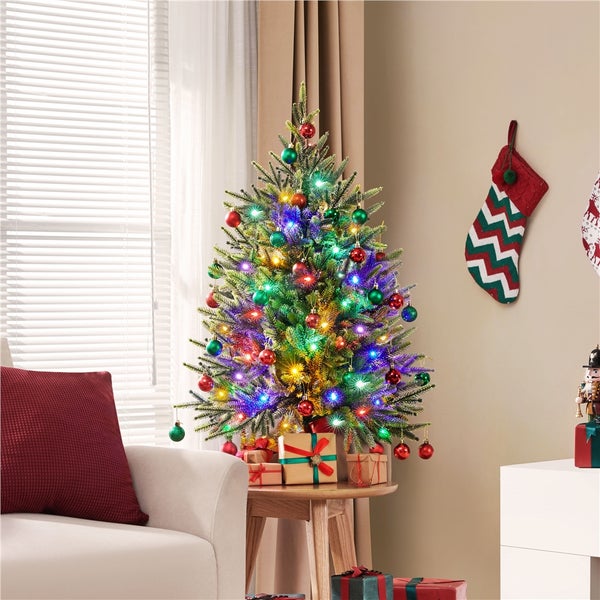 Festlich geschmückter Weihnachtsbaum mit bunten Kugeln und Lichtern im Wohnzimmer.