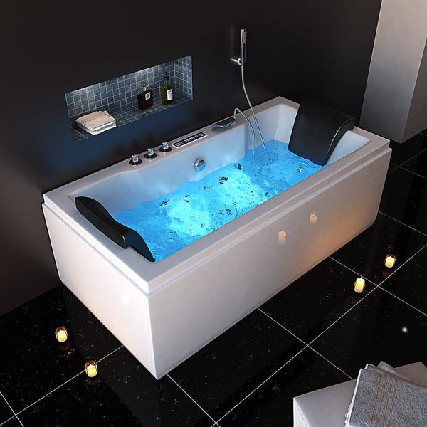 Moderne Whirlpool Badewanne mit Armaturen, Handbrause, zwei Nackenkissen und LED Unterwasserbeleuchtung in einem Badezimmer.