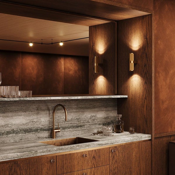 Detailaufnahme einer Bar mit Spüle, Armatur, Wandleuchten und Regalelementen in einem Raum mit Holzverkleidung.