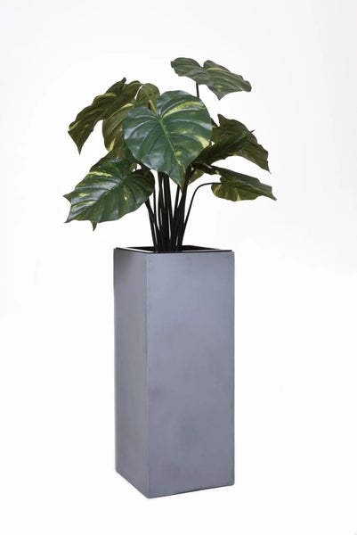 Künstliche Monstera Pflanze in einem hohen quadratischen grauen Pflanzgefäß.