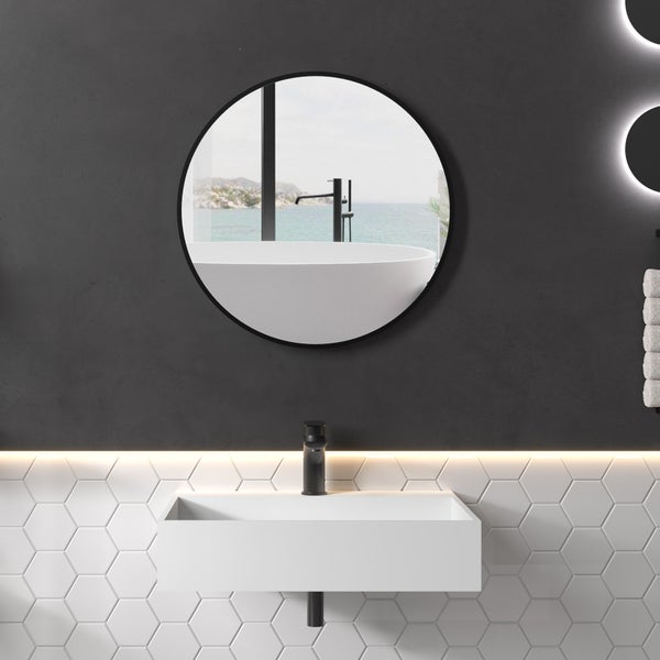 Modernes Badezimmer mit rundem Spiegel, weißem Waschbecken, schwarzer Armatur und sechseckigen Wandfliesen in minimalistischem Stil.
