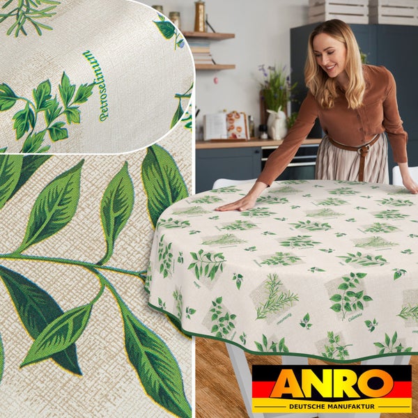Frau drapiert runde Tischdecke mit Kräutermotiv auf Tisch. ANRO Deutsche Manufaktur Logo.