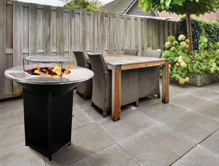 Feuerstelle mit Grillrost und Gartenmöbeln auf einer Terrasse