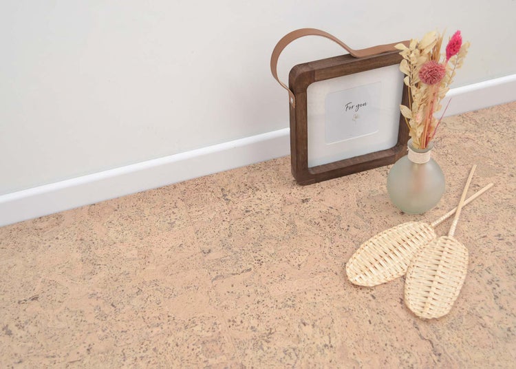 Korkboden mit natürlicher Struktur, verlegt mit Sockelleiste sowie dekorativem Holzrahmen und Trockenblumen.