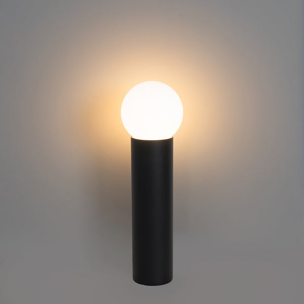 Tischleuchte mit schwarzem zylindrischem Sockel und einer leuchtenden weißen Kugellampe, die warmweißes Licht abstrahlt.