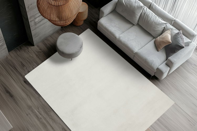 Heller Wohnzimmerteppich in einem modernen Wohnzimmer mit Sofa und Hocker aus der Vogelperspektive.