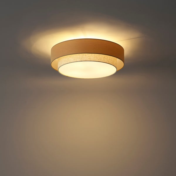 Runde Deckenleuchte mit zweilagigem Schirm aus Holz und Stoff, strahlt warmes Licht aus.