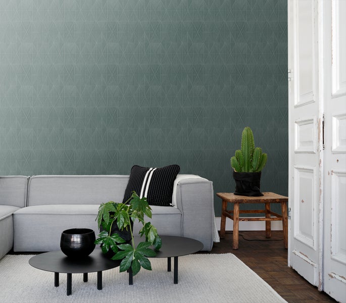 Wohnzimmer mit geometrischer Mustertapete, Sofa, Couchtisch und Pflanzen