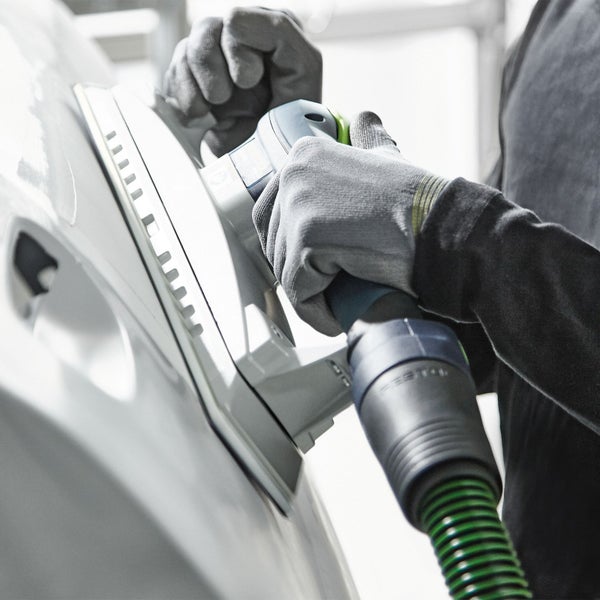 Eine Person schleift mit einem Schleifgerät ein Werkstück.