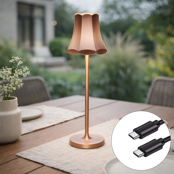 Akku-Tischleuchte für außen aus kupferfarbenem Metall mit USB-C Ladekabel auf einem Gartentisch.