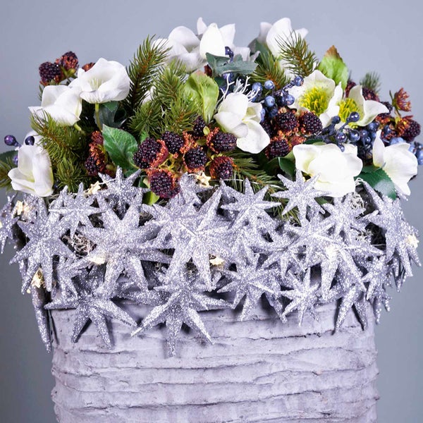Blumengesteck mit weißen Blüten, Beeren und Sternen in einem Topf