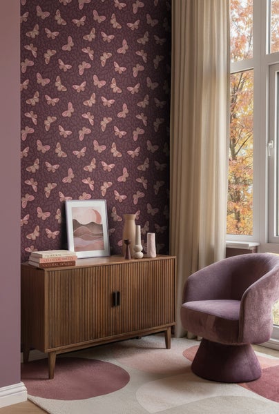 Wohnzimmer mit lilafarbener Tapete mit Schmetterlingsmuster, einem Holz-Sideboard und einem lila Sessel neben einem Fenster mit Vorhang.