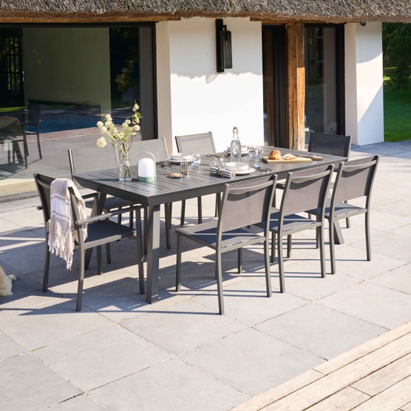 Gedeckter Gartentisch aus Metall mit Geschirr und Besteck auf einer hellen Terrasse im modernen Stil.