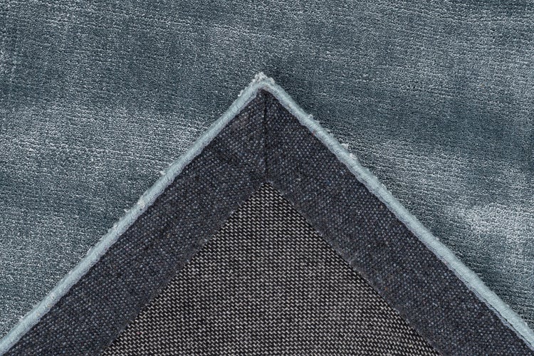 Detailansicht einer Teppichecke mit Kurzflor, gewebter Rückseite und umnähtem Rand.
