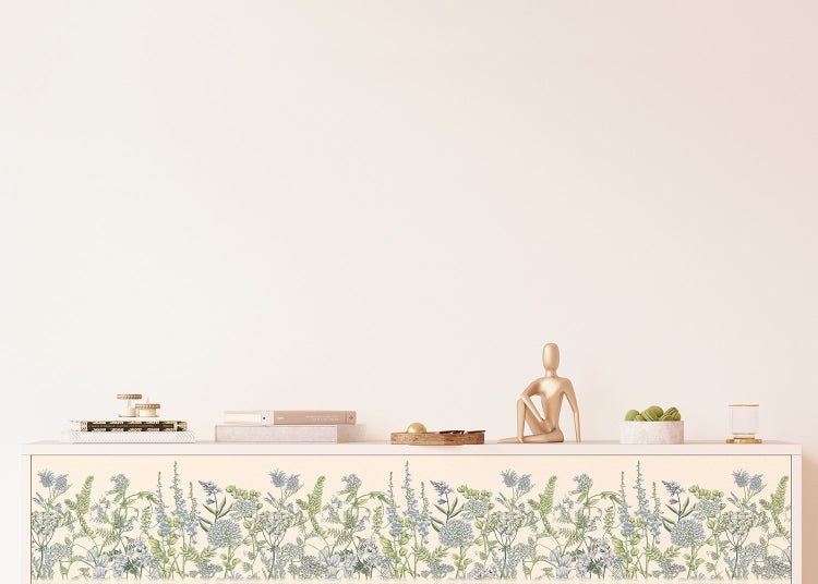 Möbelfolie mit floralem Wiesenblumenmuster auf einem Sideboard in einem hellen, aufgeräumten Raum mit Dekorationsartikeln.