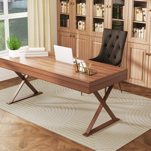 Großer Holzschreibtisch mit X-Beinen, Laptop und dunklem Lederstuhl vor einem Bücherregal aus Holz in einem hellen, organisierten Arbeitszimmer.