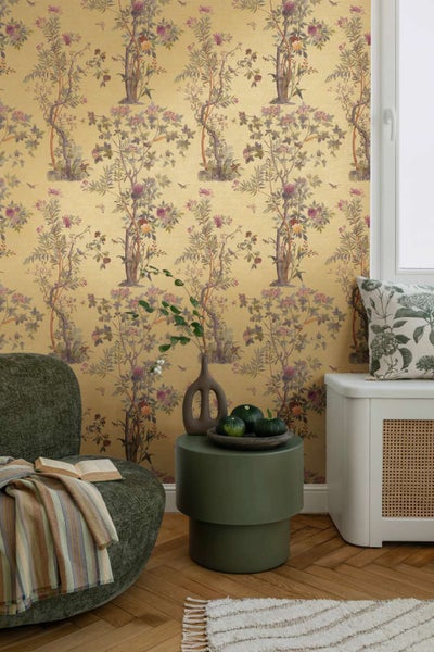 Vliestapete mit floralem Chinoiserie Motiv in einem stilvoll eingerichteten Wohnbereich mit Sessel und Beistelltisch.