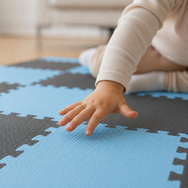 Ein Kind spielt auf einer weichen Spielmatte aus Schaumstoff mit ineinandergreifenden Puzzleteilen im Innenbereich.