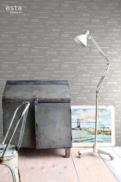 Dekorative Szene mit einer alten Truhe, einem Stuhl, einer Stehlampe und einem Bild vor einer gemusterten Tapete.