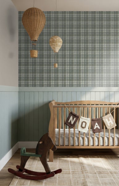 Helles, ordentliches Kinderzimmer mit Gitterbett aus Holz, Schaukelpferd, karierter Tapete, Wandtäfelung und Heißluftballons aus Korbgeflecht.