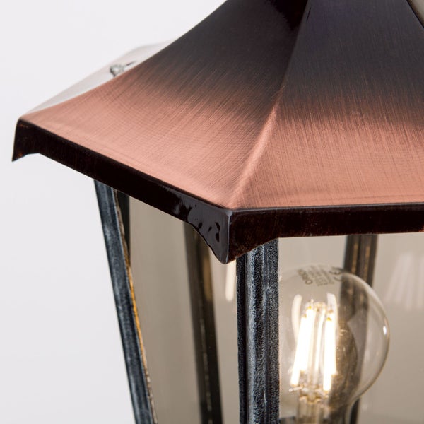 Nahaufnahme einer Außenlaterne mit kupferfarbenem Dach und leuchtendem LED-Filament-Leuchtmittel hinter Glas.