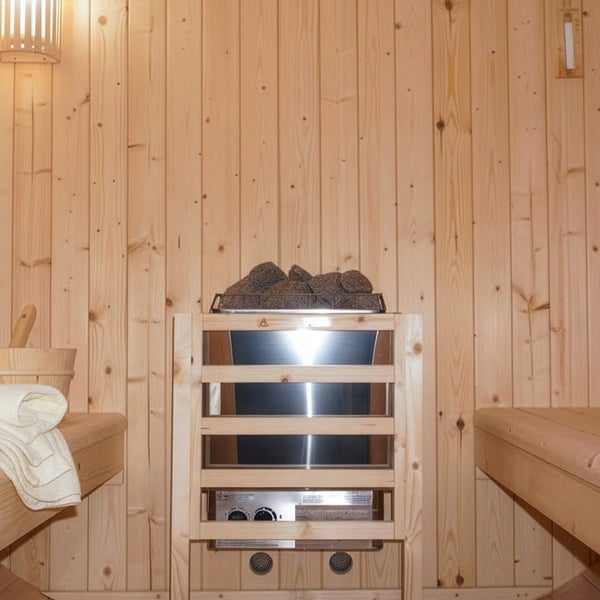 Saunaofen mit Saunasteinen in einer Holzkabine mit zwei Saunabänken und einer Saunaleuchte