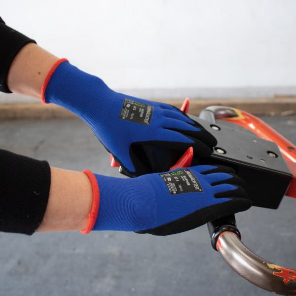Person trägt Montagehandschuhe Leibwaechter Saphir bei der Bedienung einer Maschine.