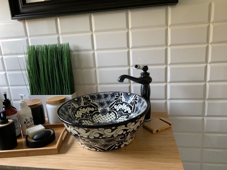 Badezimmer Waschtisch mit gemusterter Aufsatzwaschbecken, Armatur und Badaccessoires auf Holzablage.