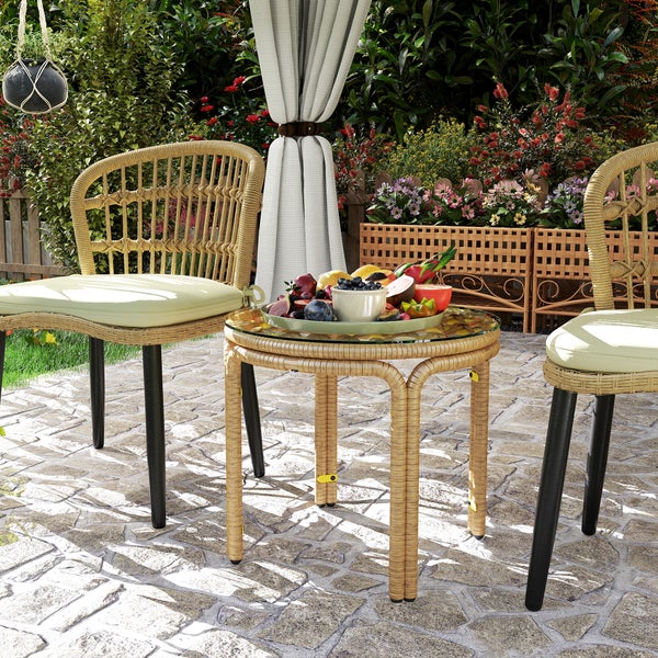 Gartenszene mit Rattanstühlen, Tisch mit Glasplatte und Obstschale
