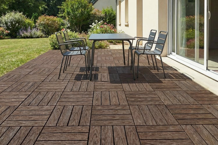 Terrasse mit Holzklickfliesen, belegt mit einem Metallgartentisch und vier passenden Stühlen vor einem Haus im Garten.