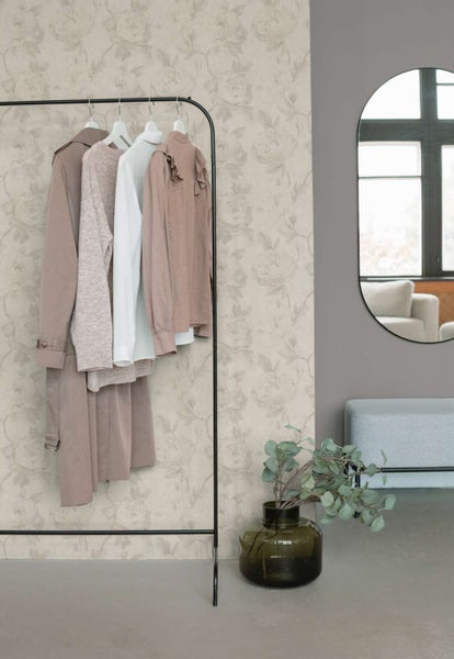 Wohnraum mit floraler Tapete, einem schwarzen Kleiderständer mit Kleidung, einem runden Spiegel und einer Sitzbank in einem modernen Interieur.
