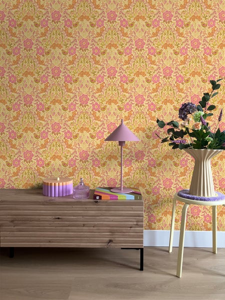 Dekoratives Zimmer mit gemusterter Tapete, Kommode und Beistelltisch mit Blumen