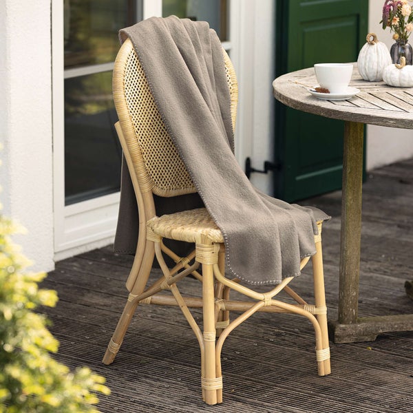 Rattan-Stuhl mit grauer Decke auf Terrasse